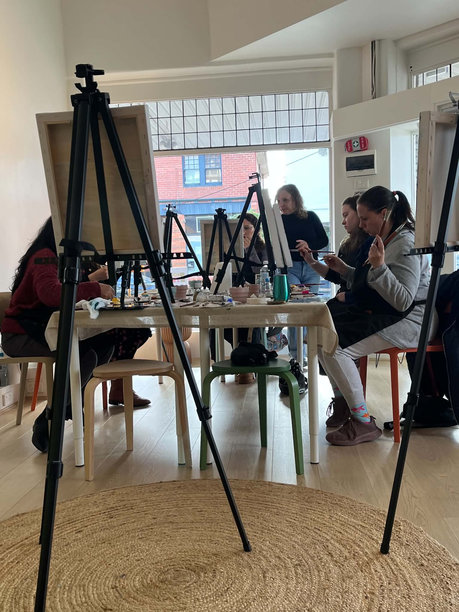 Students painting at easels, seen from across the studio table