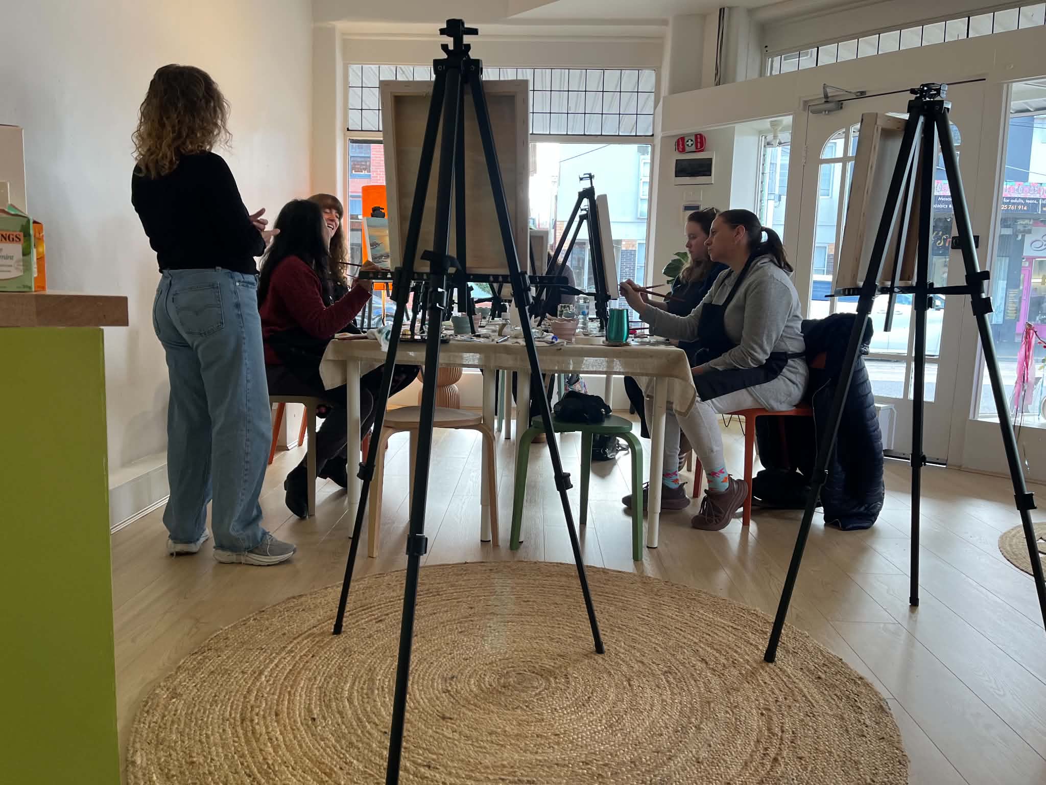 The class instructor talking with a student beside her easel
