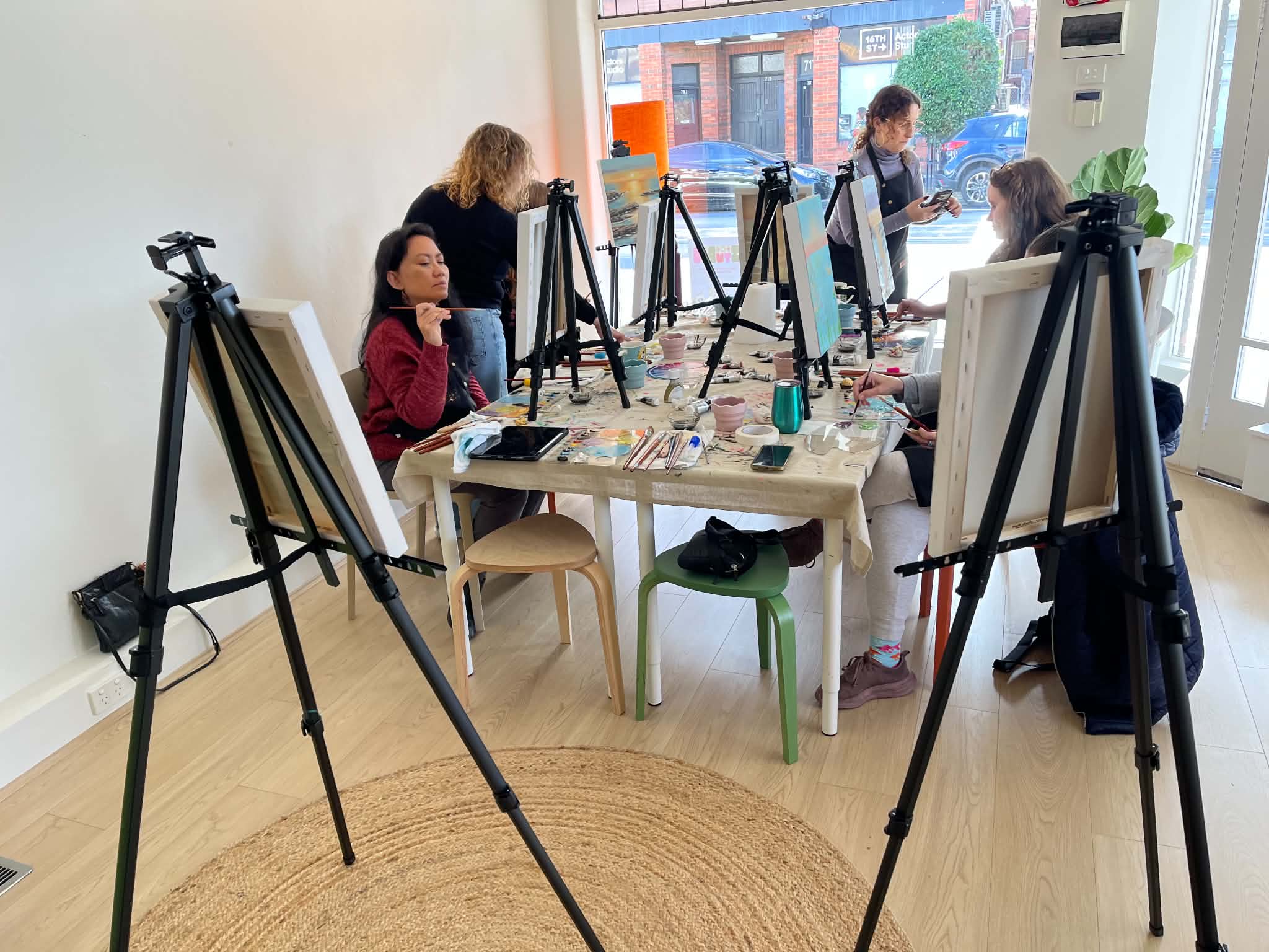 Students seated together at a shared table, painting